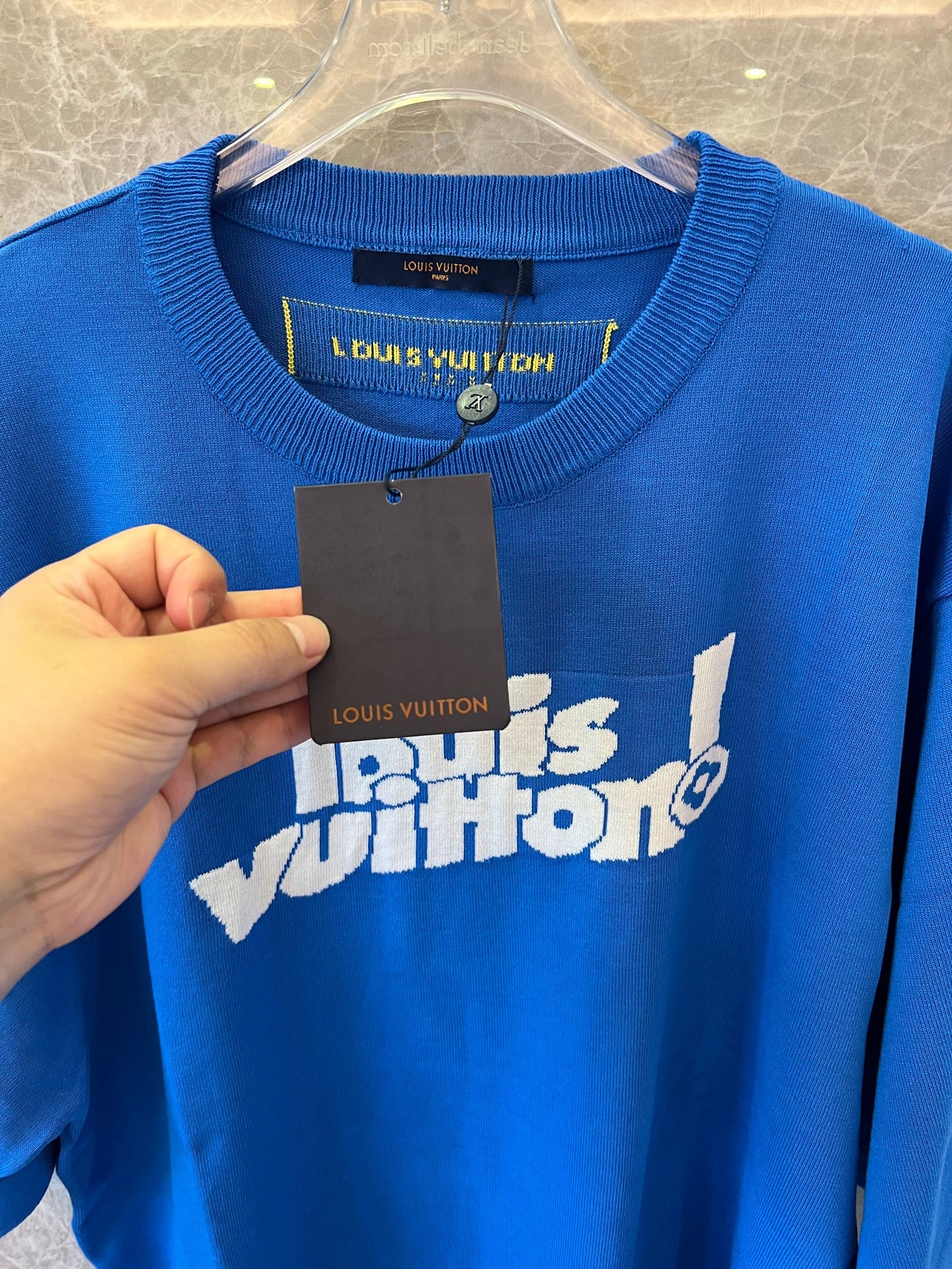 Camiseta azul de Louis Vuitton con el logo "Louis Vuitton!" en la parte delantera y etiqueta amarilla de París.