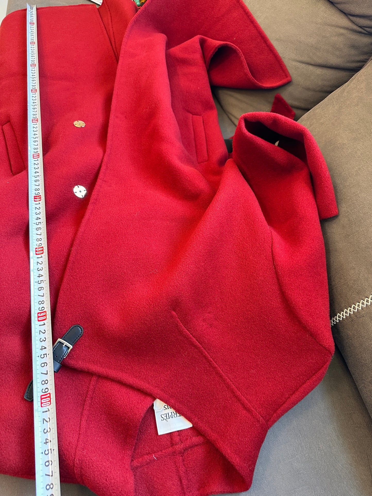 Abrigo de lana roja Hermes con cuello asimétrico y hebilla de cuero.