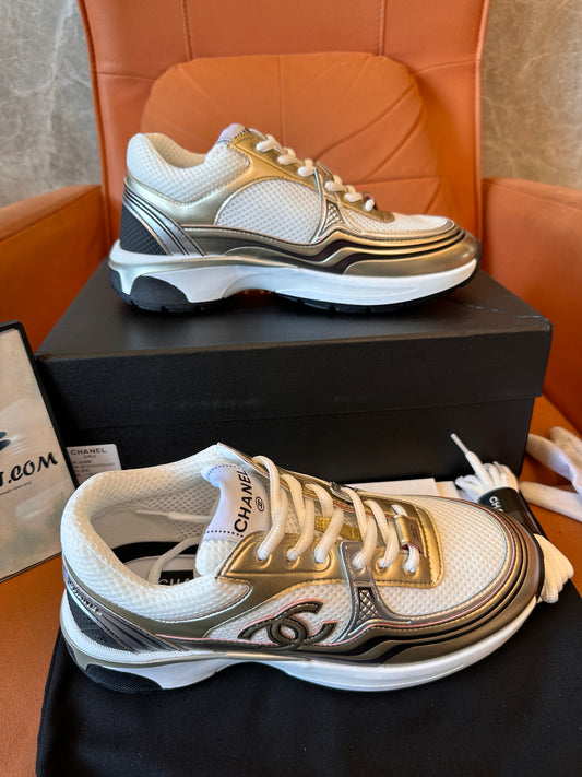Chanel CC Trainers: zapatillas blancas y doradas con el icónico logotipo.