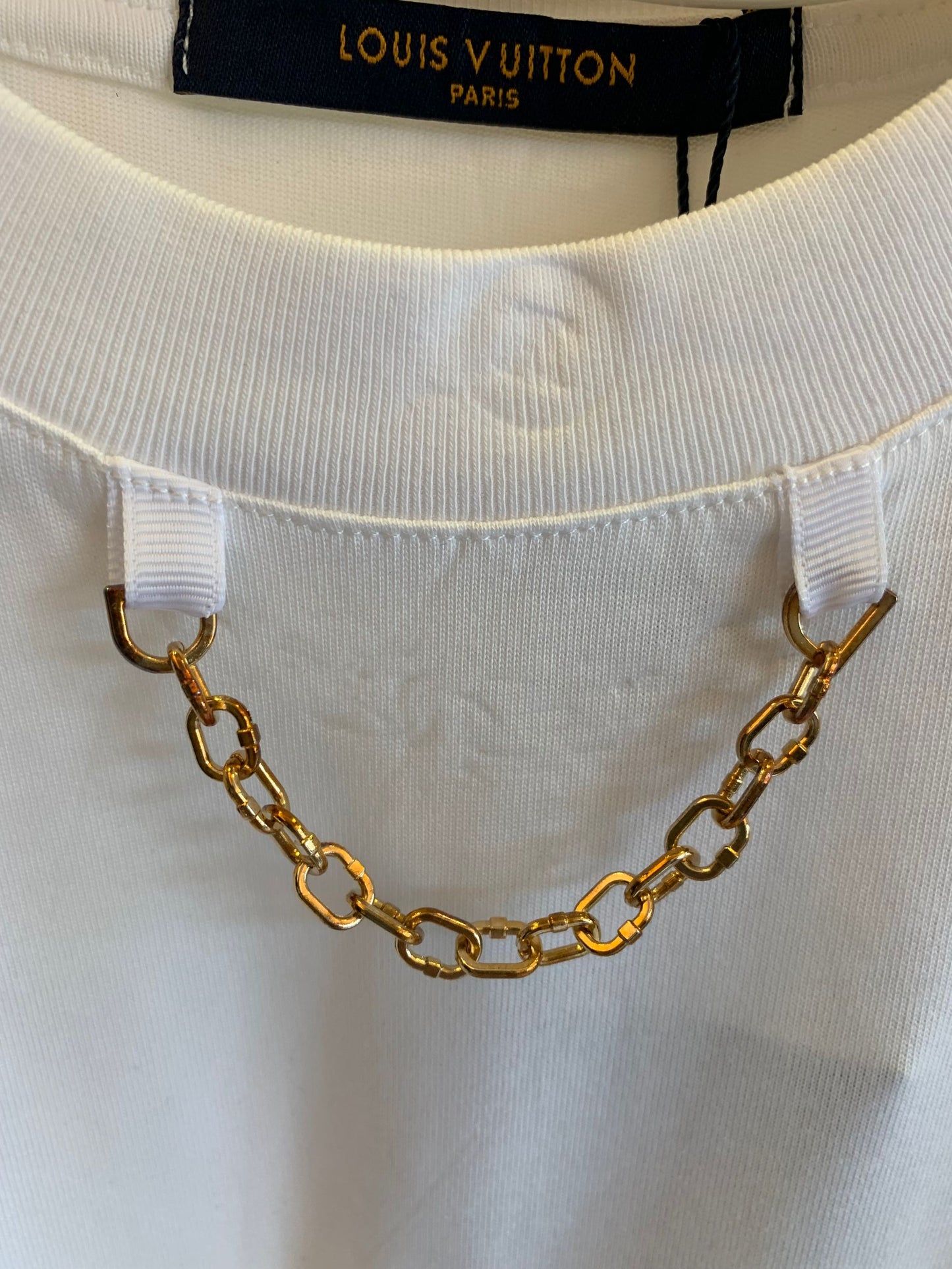 Camiseta blanca Louis Vuitton con detalle de cadena dorada y logotipo bordado
