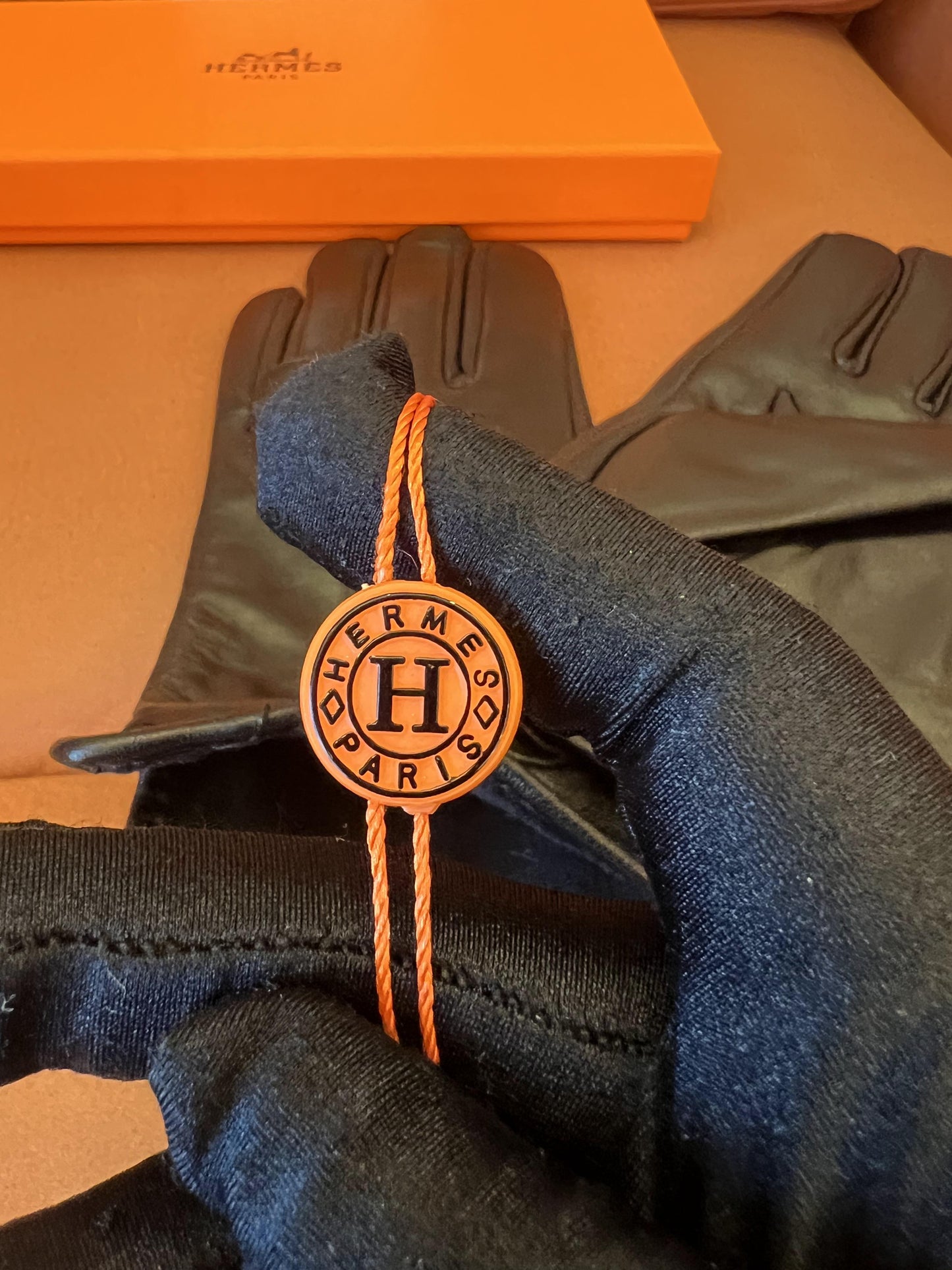 Guantes Hermès de piel negra: elegante piel de cordero con el logo H dorado.