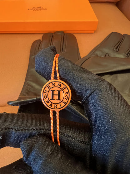 Guantes Hermès de piel negra: elegante piel de cordero con el logo H dorado.