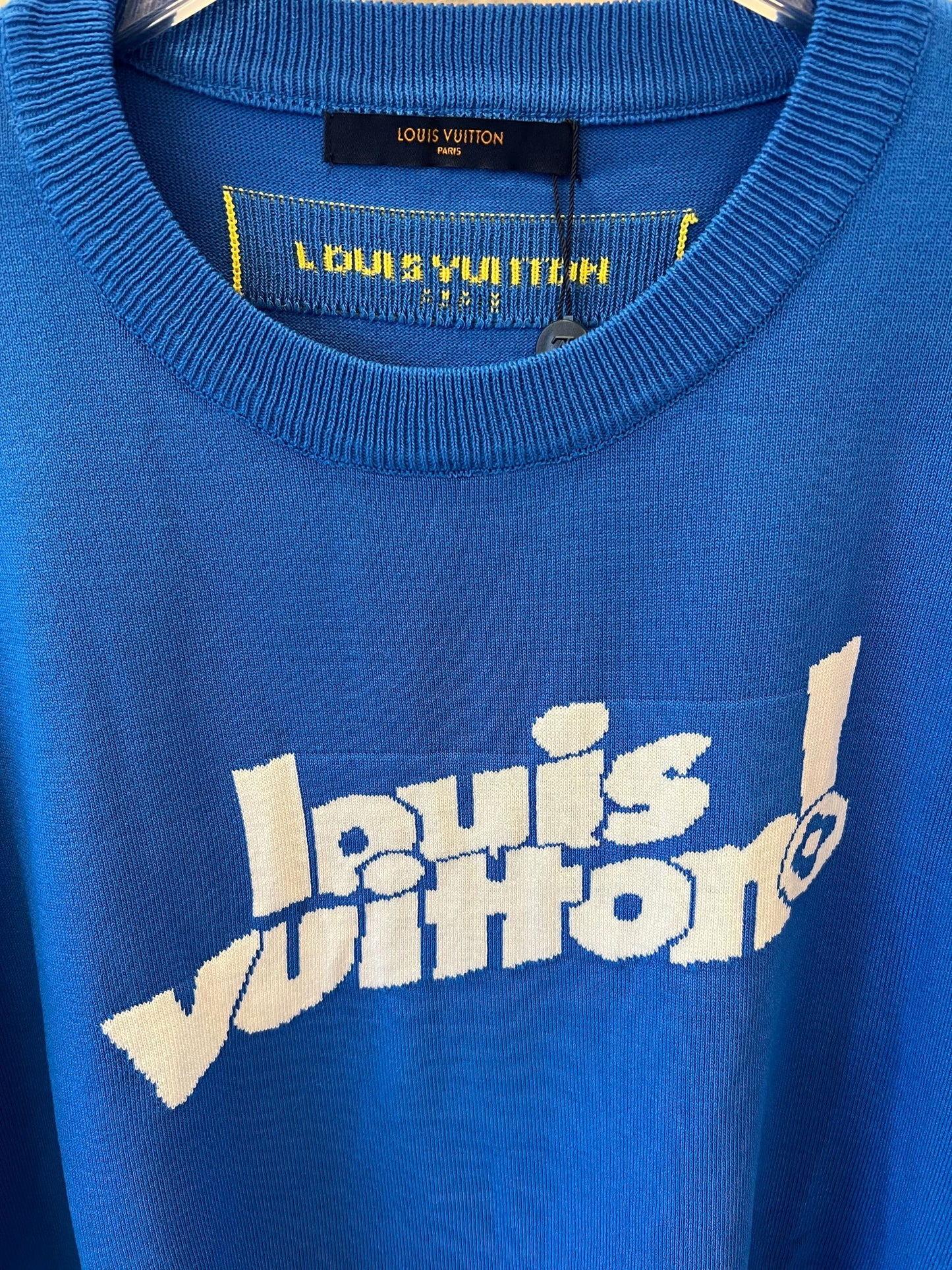 Camiseta azul Louis Vuitton com logotipo "Louis Vuitton!" na frente e etiqueta amarela Paris