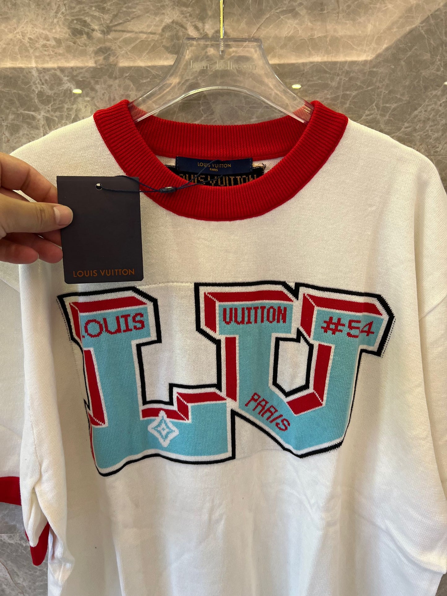 Camiseta blanca de Louis Vuitton con el llamativo logotipo LV y detalles de canalé rojo.
