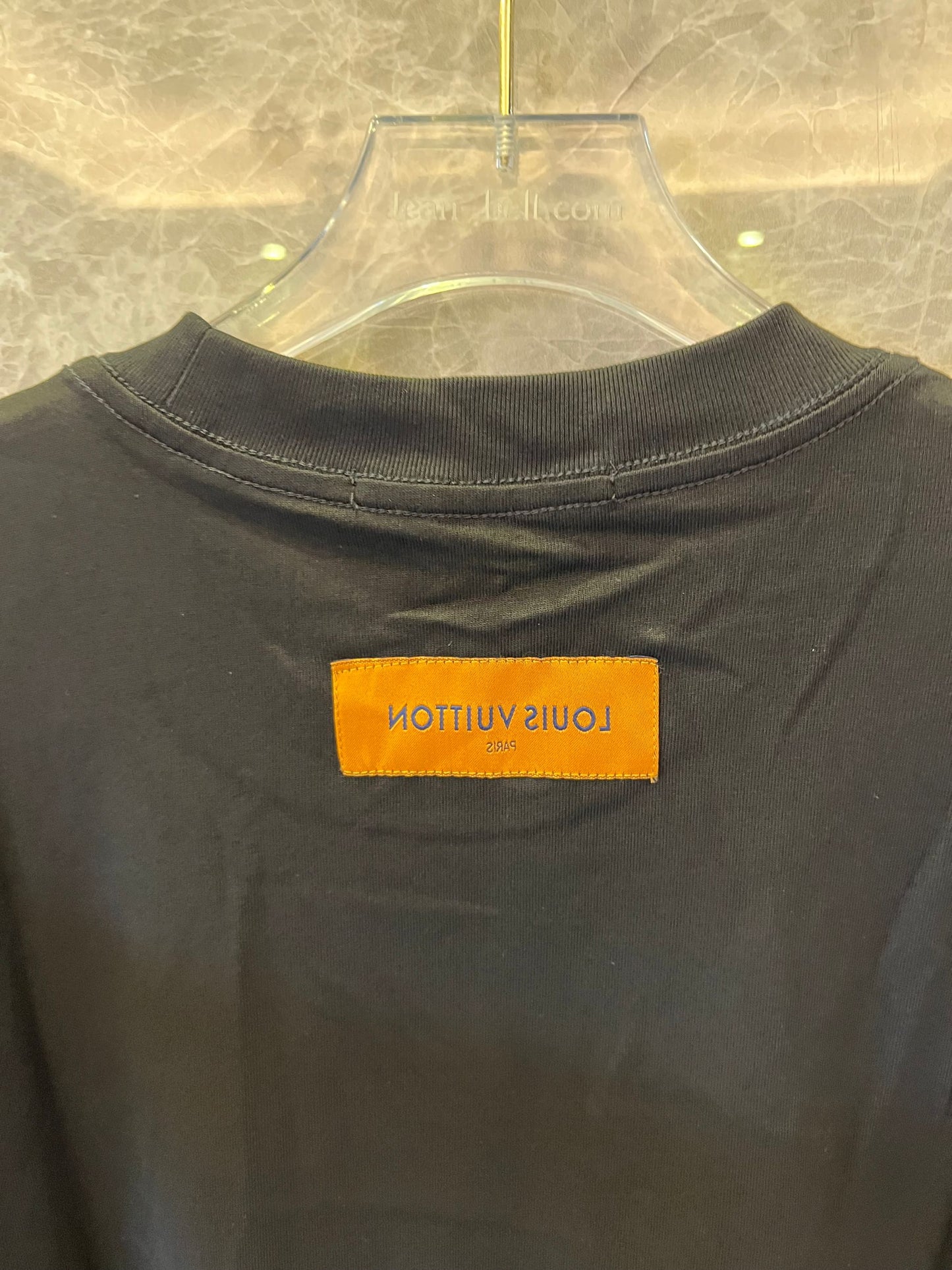 Camiseta negra de Louis Vuitton con el gráfico "The Louis Vuittons" y una etiqueta naranja de París.