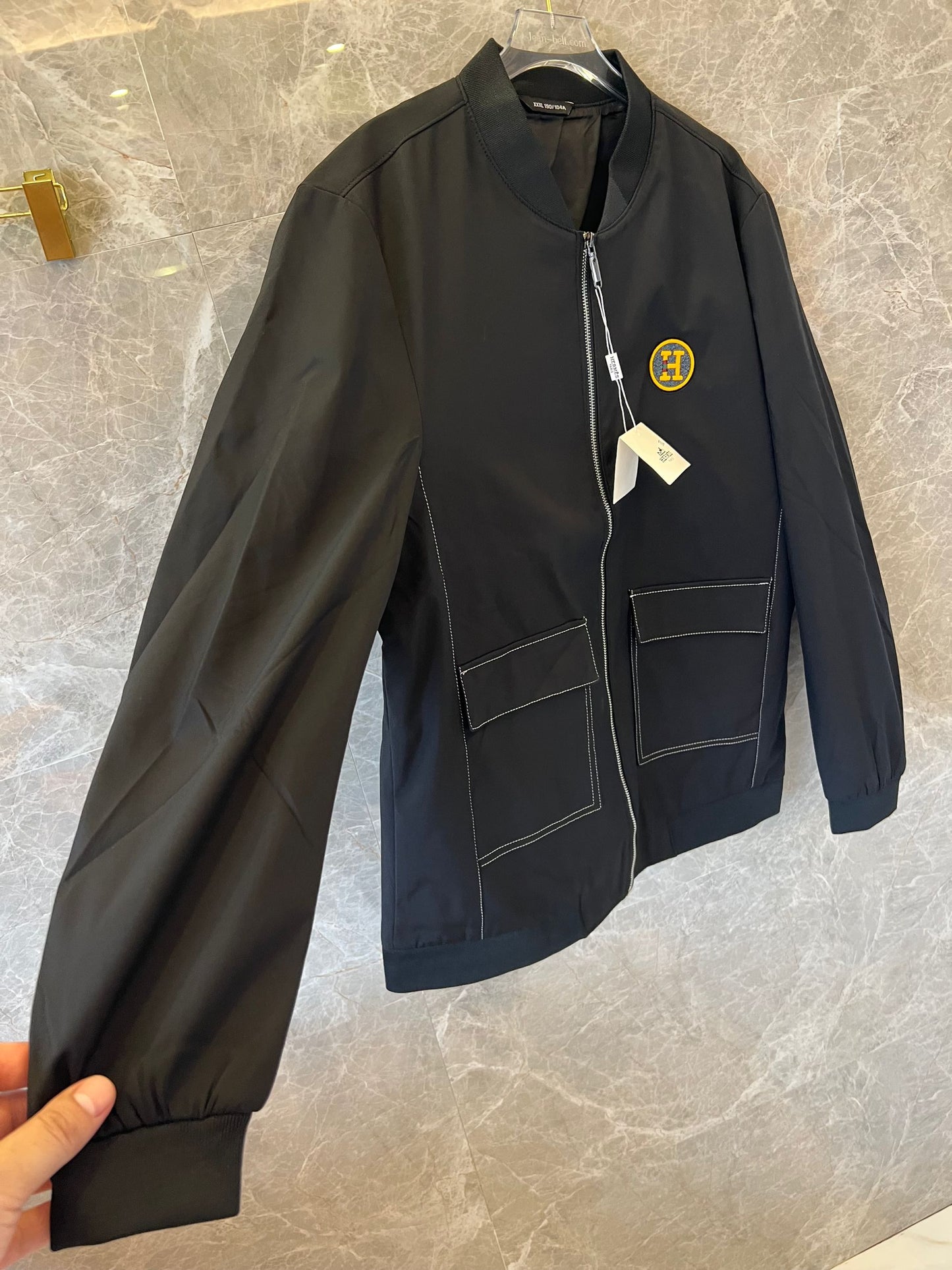 Chaqueta bomber de nailon negra de Hermès con parche del logotipo "H" amarillo.