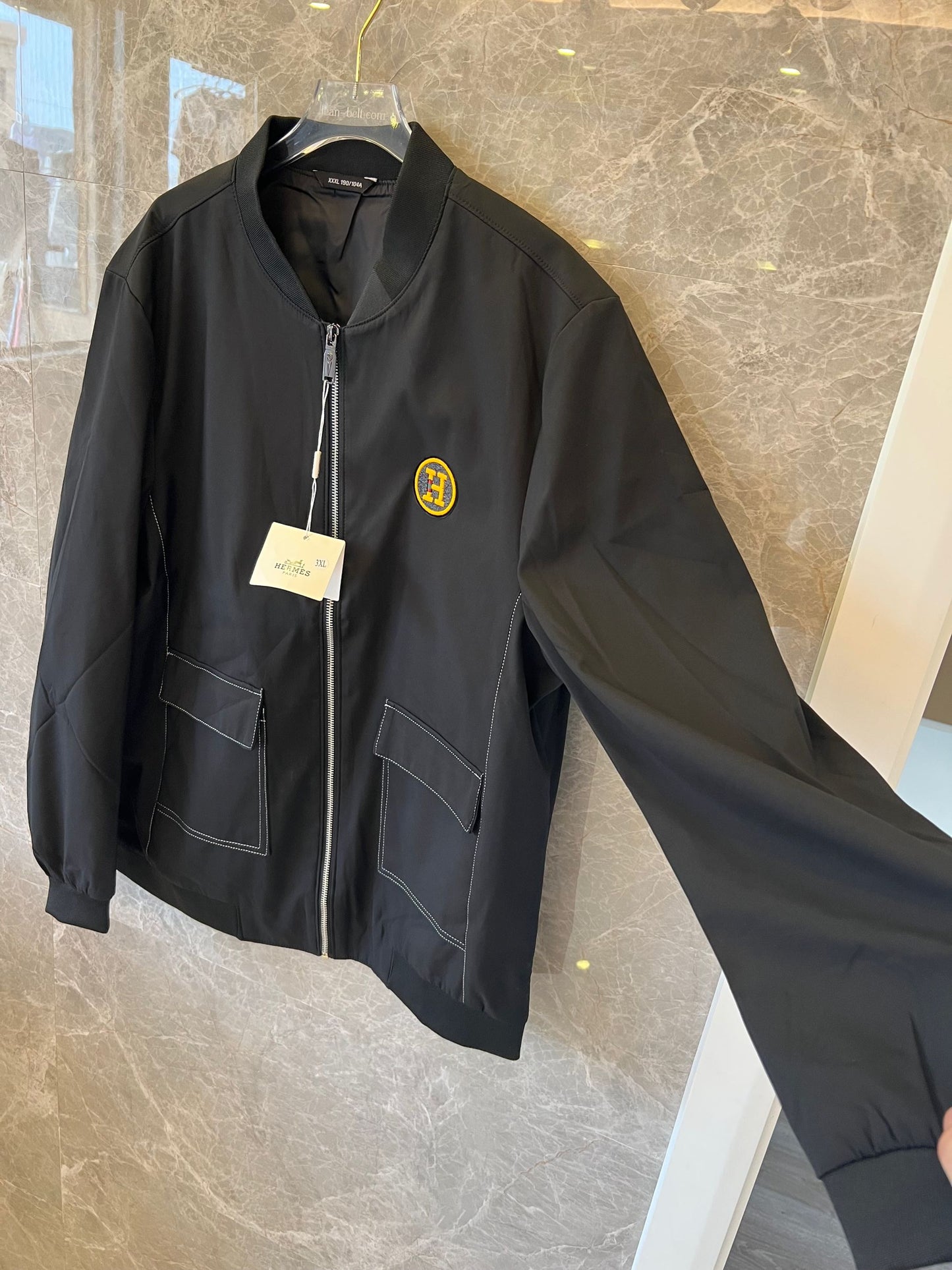 Chaqueta bomber de nailon negra de Hermès con parche del logotipo "H" amarillo.