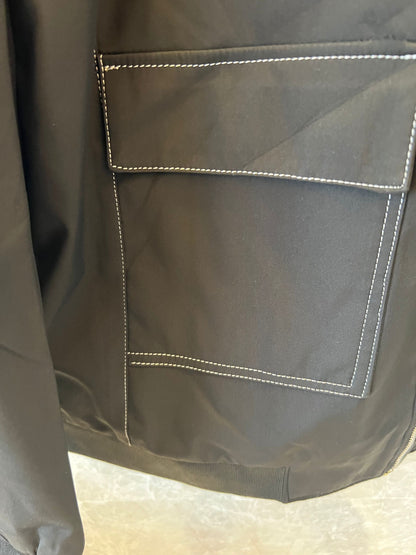 Chaqueta bomber de nailon negra de Hermès con parche del logotipo "H" amarillo.