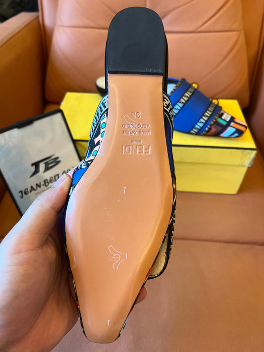Sandalias azules tipo slide para mujer de Fendi con tiras estampadas y detalles dorados.