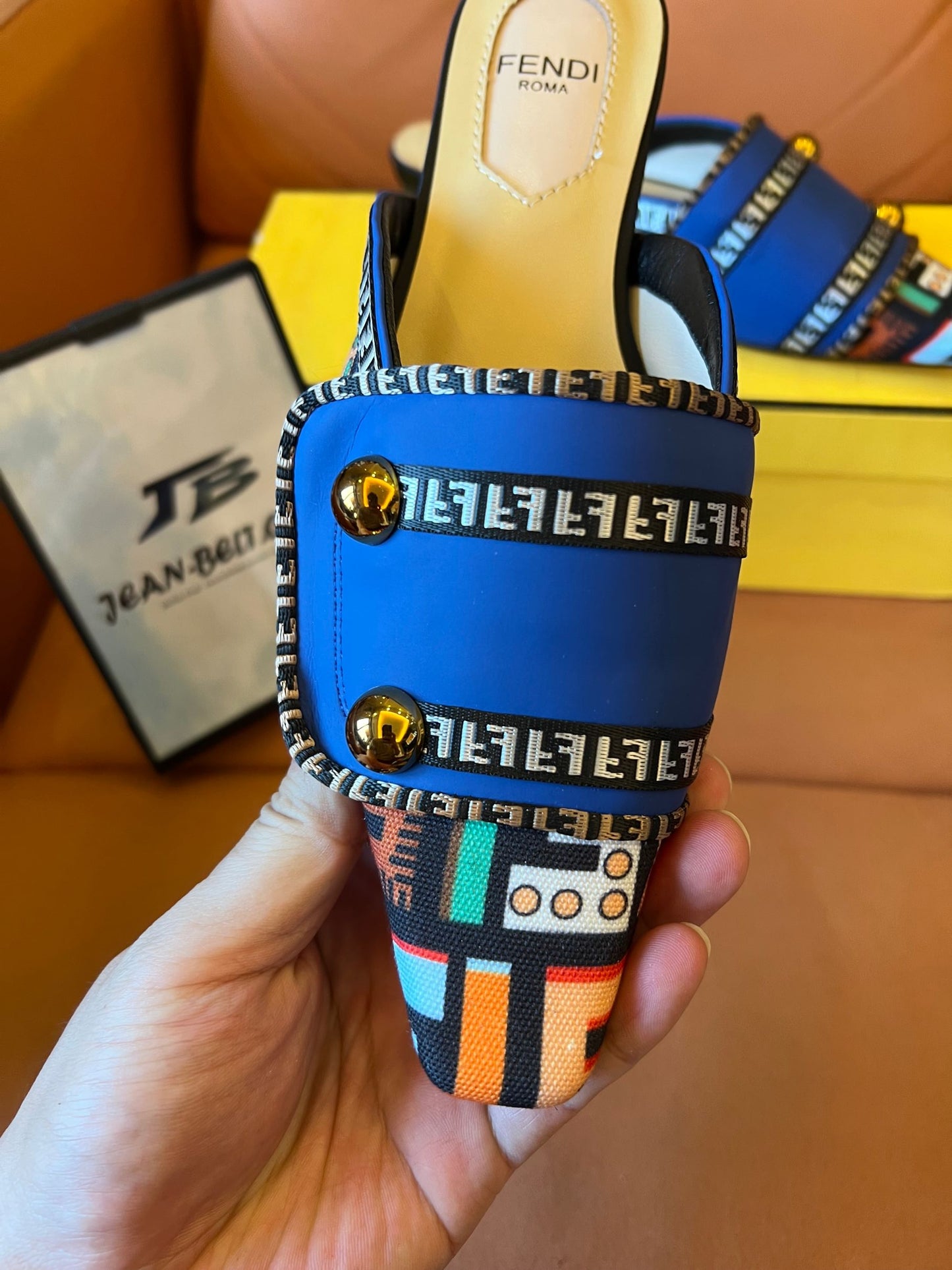 Sandalias azules tipo slide para mujer de Fendi con tiras estampadas y detalles dorados.