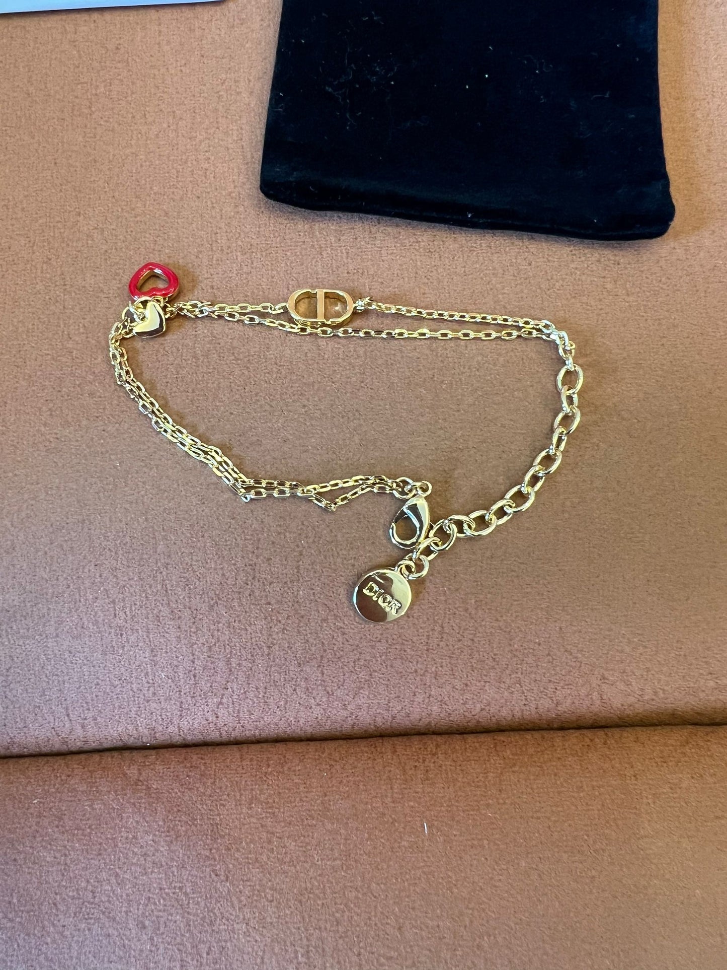 Pulsera de cadena dorada Dior con el icónico CD y charms de corazón