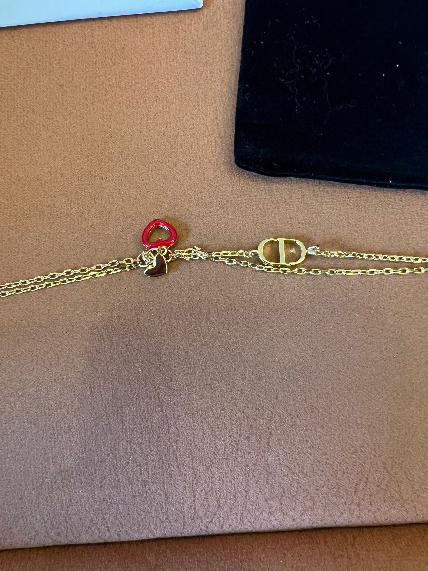 Pulsera de cadena dorada Dior con el icónico CD y charms de corazón