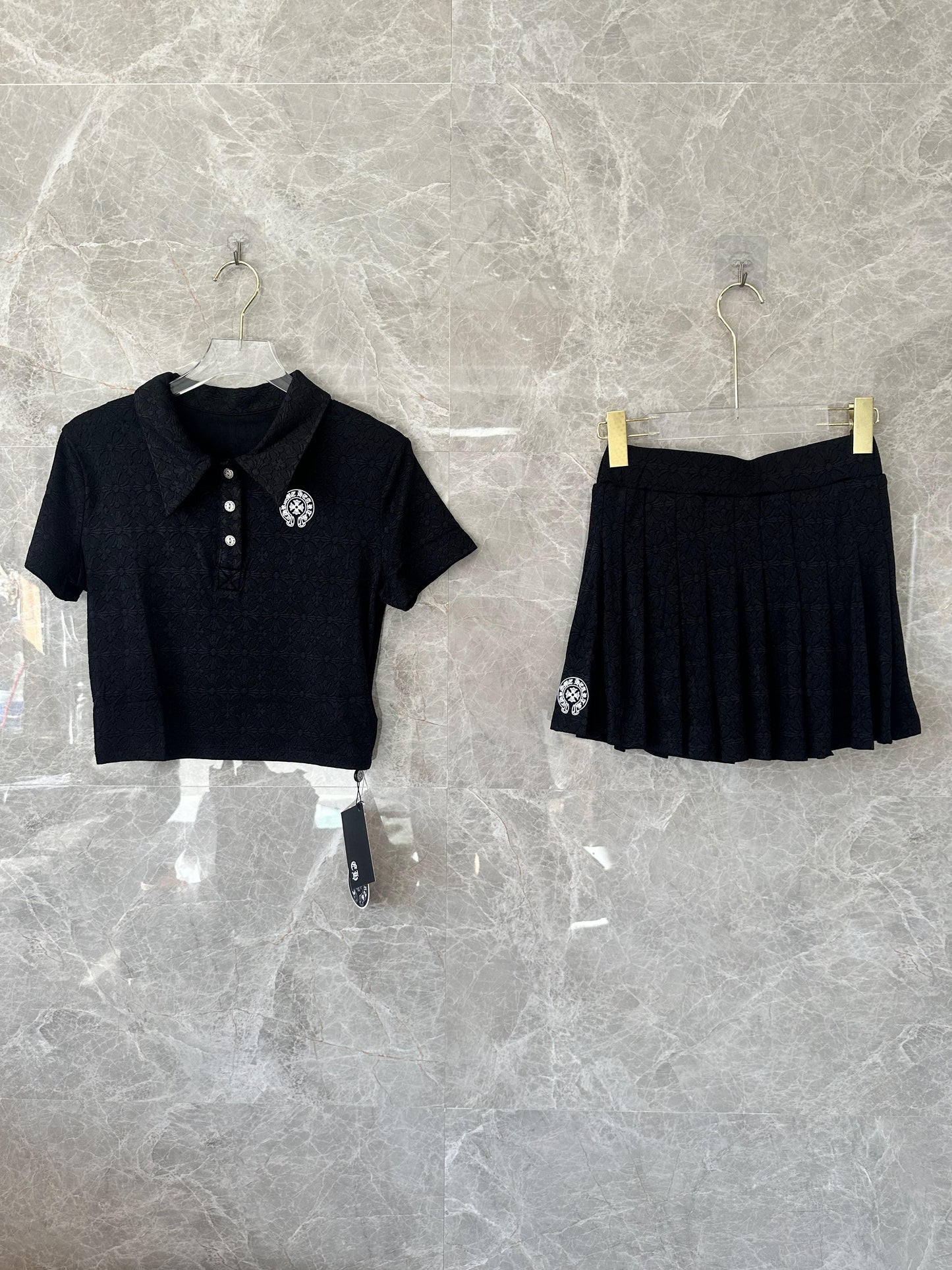 Conjunto de top corto tipo polo bordado negro y minifalda plisada de Chrome Hearts