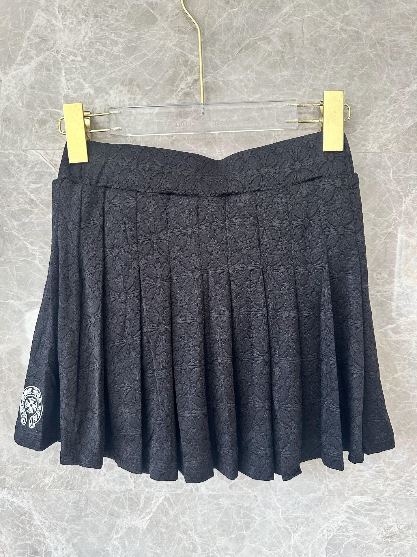 Conjunto de top corto tipo polo bordado negro y minifalda plisada de Chrome Hearts