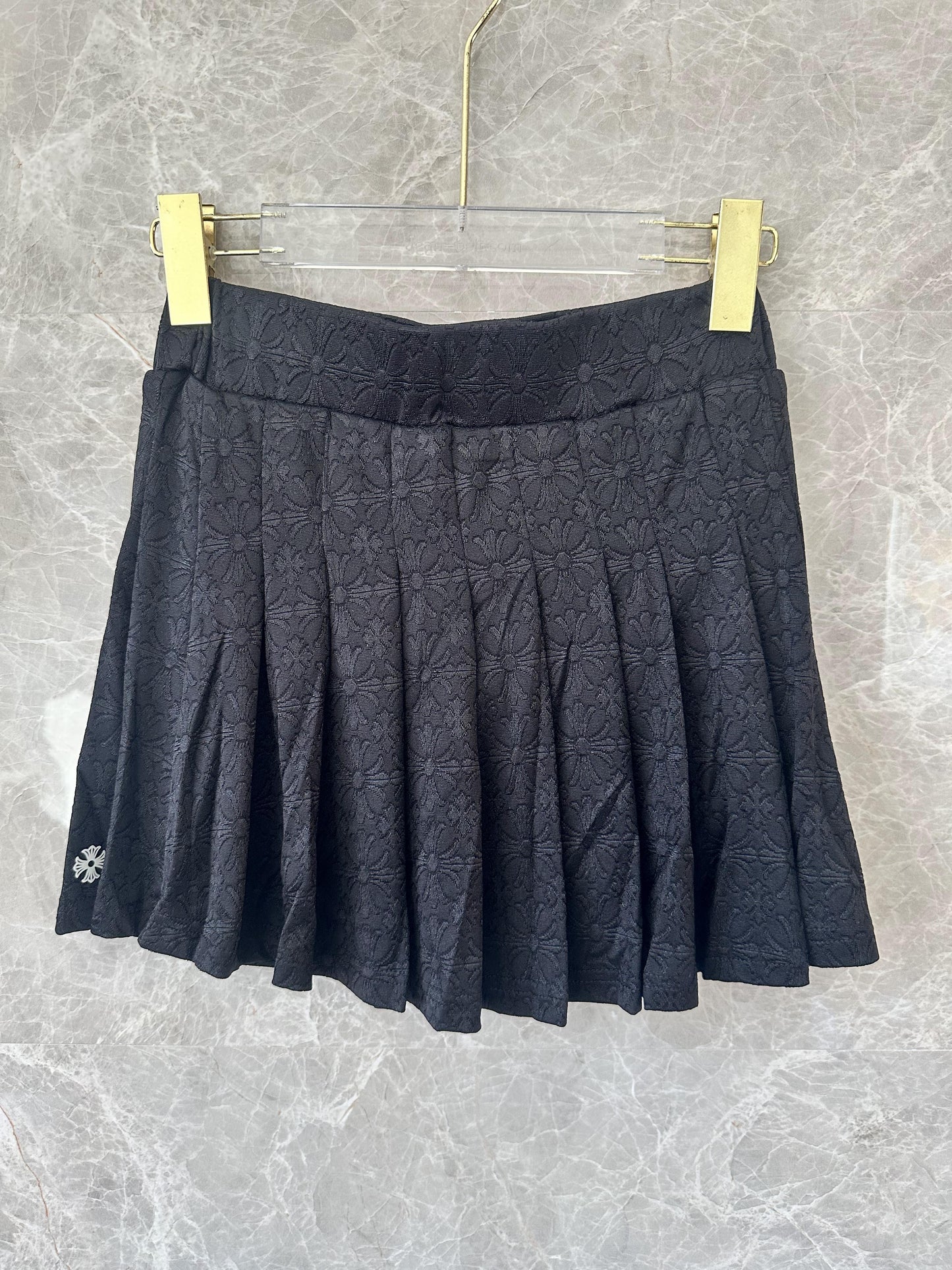 Conjunto de top corto tipo polo bordado negro y minifalda plisada de Chrome Hearts