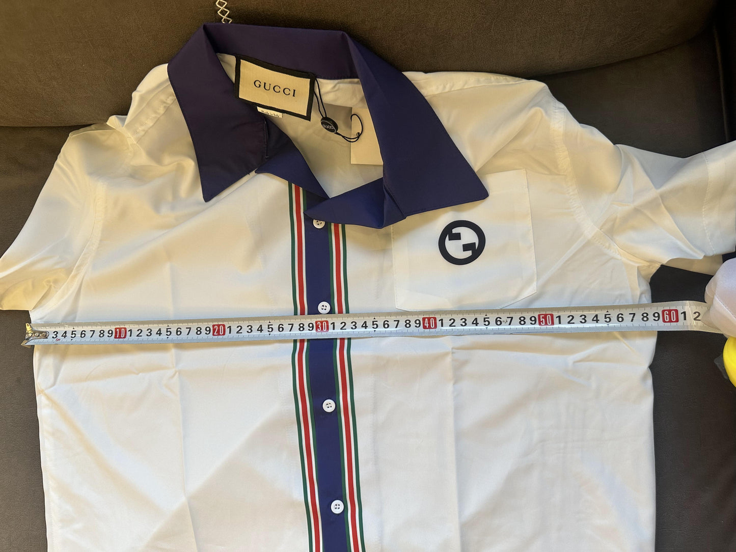 Camisa Gucci blanca de manga corta con botones, cuello azul marino y rayas.