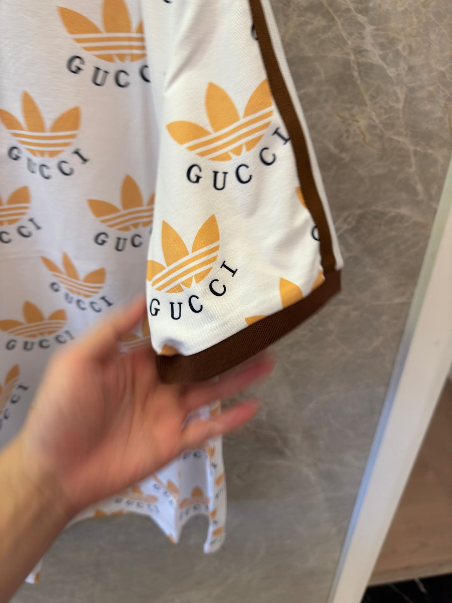 Polo con estampado de trébol de Gucci x Adidas en blanco y marrón con logotipos icónicos