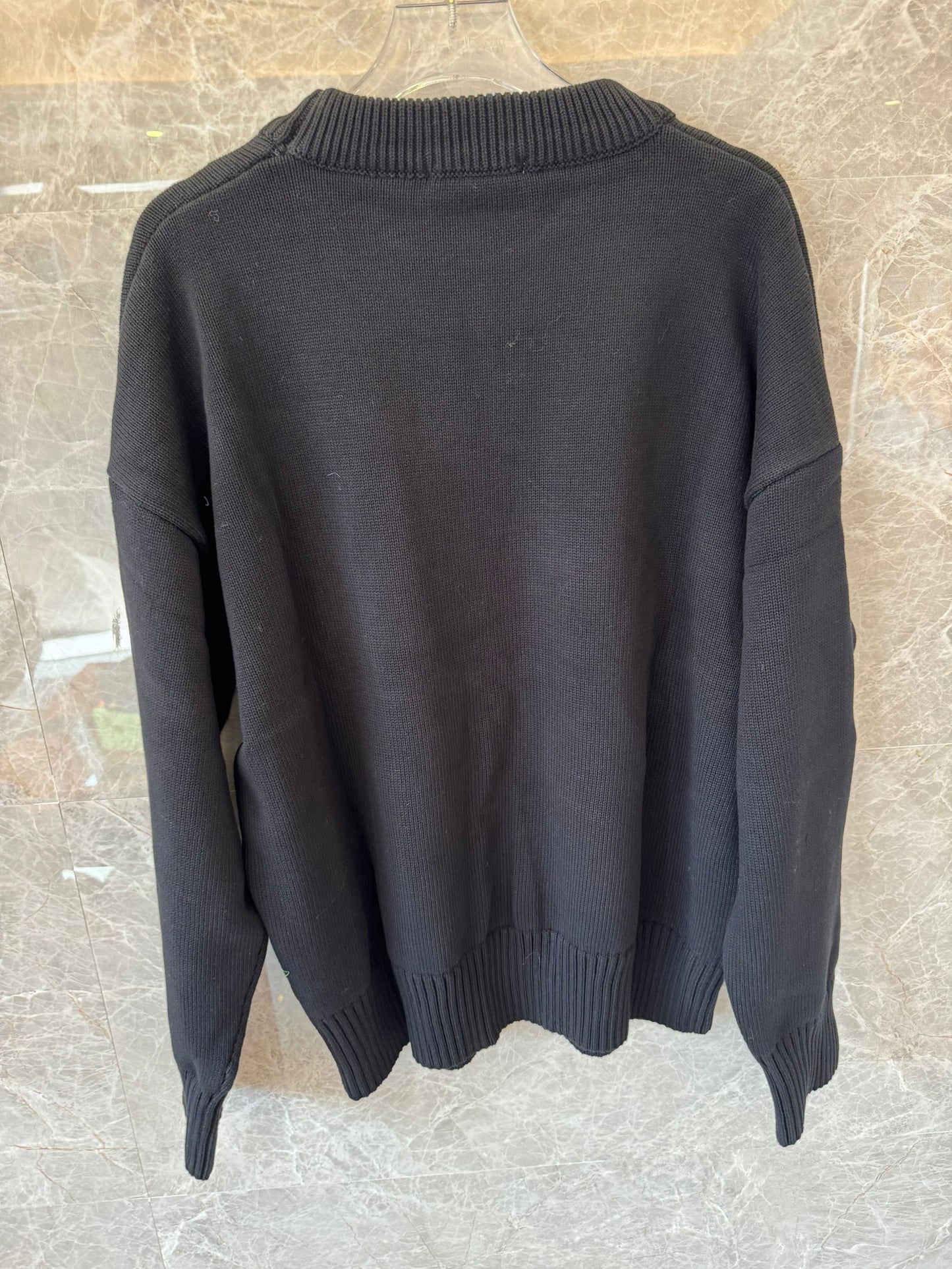 Suéter de punto negro con bordado de corazón de Ami: un jersey acogedor con el característico logotipo "A" rojo.